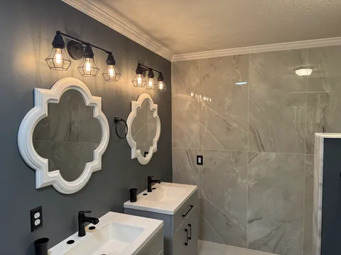 Double vanity with decorative mirrors and gray blue walls
