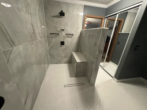 Gray tiled shower with bench and linear drain