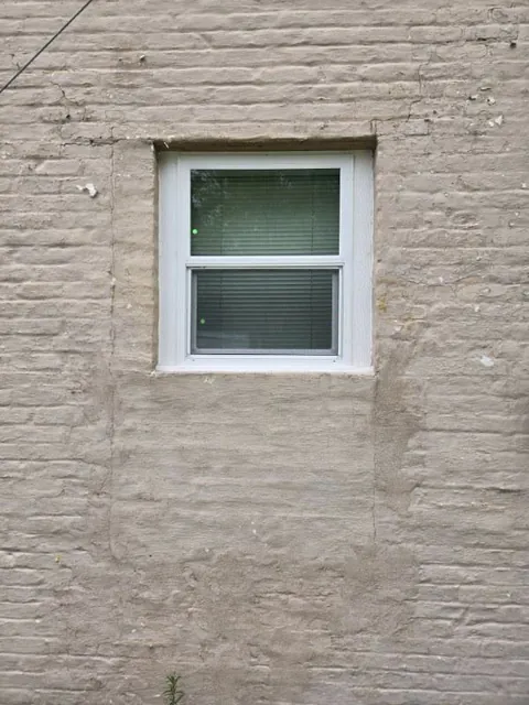 Small white framed window in a masonry wall