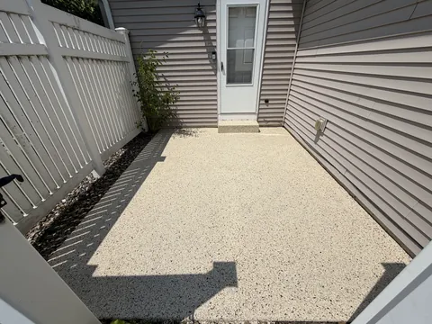 Speckled walkway between siding and a fence