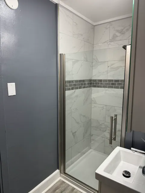 Tiled shower enclosure with a dark horizontal accent band