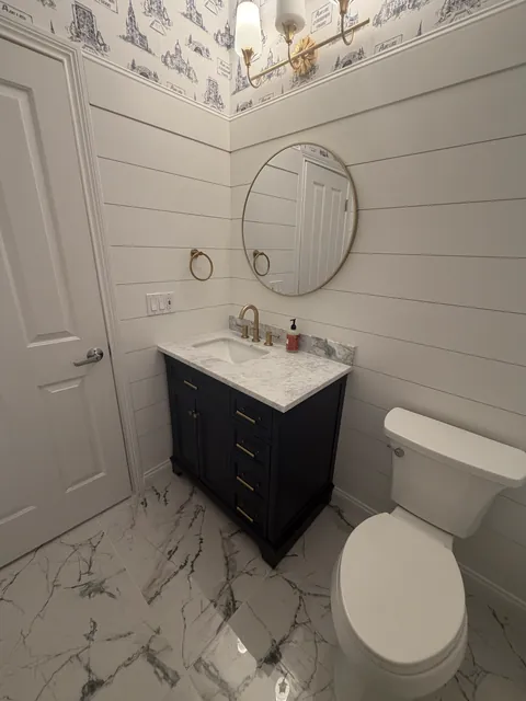Dark vanity with a round mirror and white shiplap walls