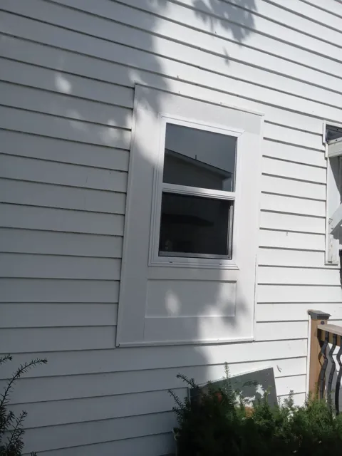 White framed window set into gray siding