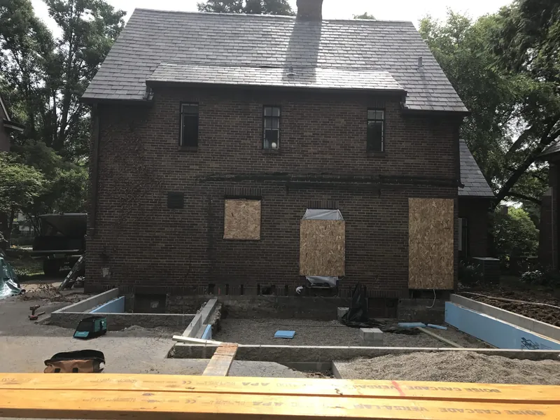 Existing brick exterior and early foundation work before the addition was framed