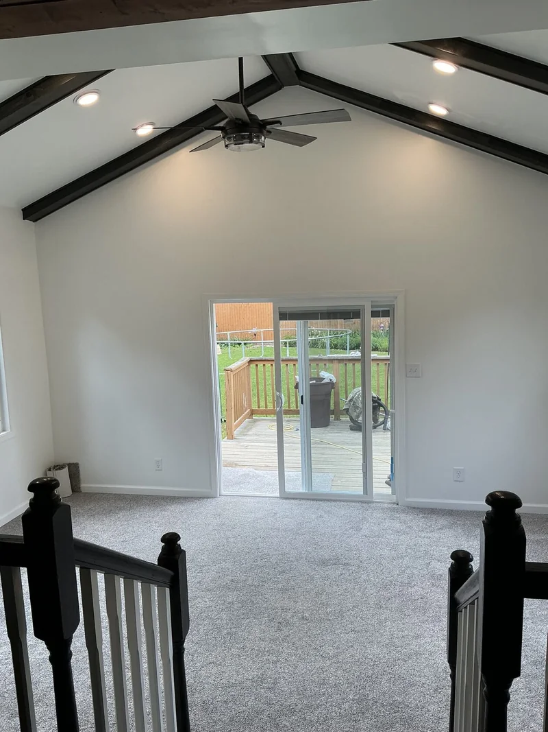 Interior with a vaulted ceiling, dark beams and sliding glass door